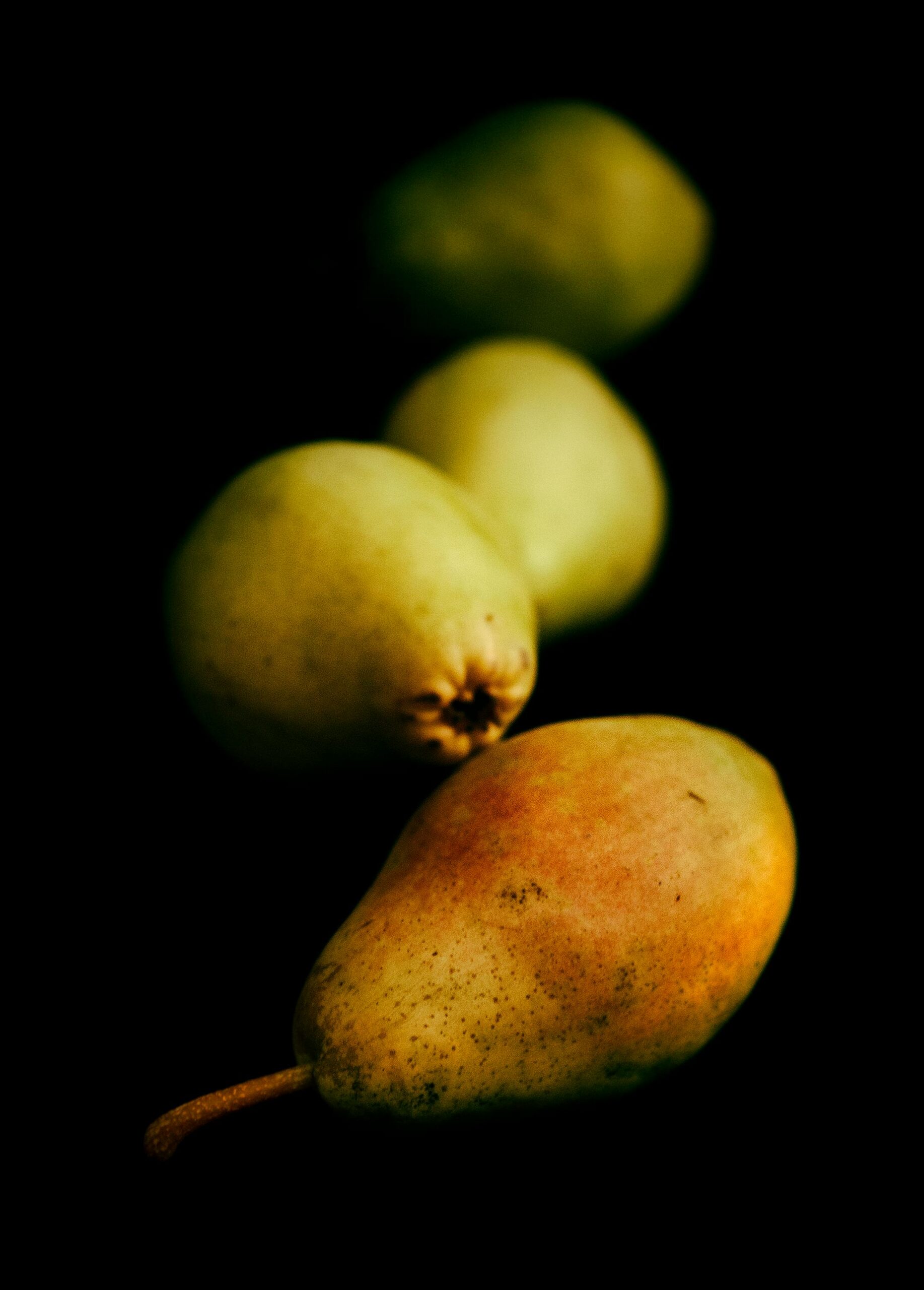 A close-up of fresh pears arranged artistically, showcasing vibrant colors against a dark backdrop.